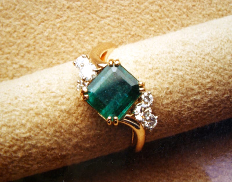 Emerald and diamond halo engagement ring in gold setting